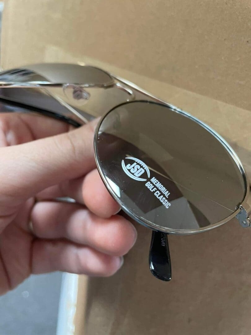 A person holding up their sunglasses to see them